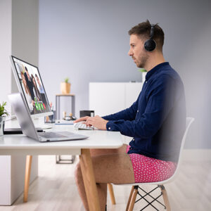 Homme en chemise bleue et caleçon rose participant à une visioconférence